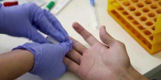 在接受covid-19测试前，戴着手套的医生手可以为男性的手指消毒
