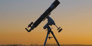 望远镜的轮廓和遥远的城市地平线。