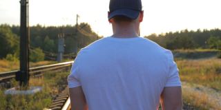 那家伙在夕阳的余晖中走在铁路上。
