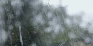一场倾盆大雨的窗外景色。水滴从玻璃上流下。关闭了。秋天的季节