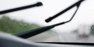 在能见度有限的情况下驾驶汽车:大雨，雨刷清洁挡风玻璃。高速公路上迎面而来的车辆开着前灯。恶劣天气条件下的道路安全。从车内看