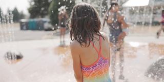 小女孩在水上公园的喷泉里玩