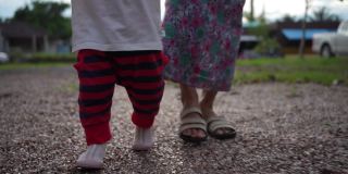奶奶拉着小女孩的手学走路。