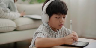 一个男孩在家里用笔记本电脑学习在线课程