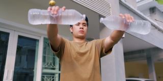 亚洲男人在家用水瓶锻炼。