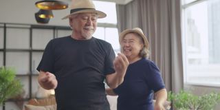 幸福退休亚洲人爱夫妇退休老夫妇在家，亚洲老夫妇一起跳舞笑笑喜气在客厅在家隔离呆在家封锁概念