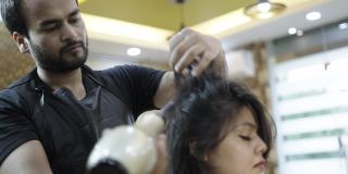 美容院的一名工作人员在给女顾客理发时正在用吹风机