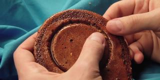 男人的手把糖饼干掰成一个圆圈的形状。