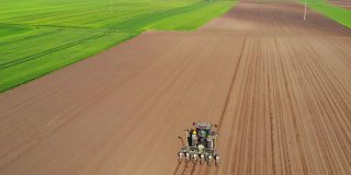 无人机拍摄的农民用拖拉机播种作物
