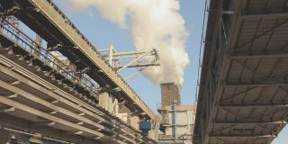 从工厂的烟囱里冒出来的浓浓的白烟。对环境的危害。大型冶金厂的外部。从工厂的烟囱中排放出的白烟。