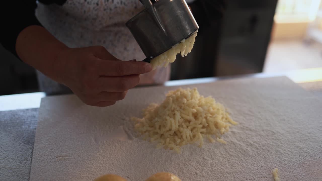 在意大利面工厂里，一名妇女正在用土豆榨汁机制作新鲜的手工土豆团