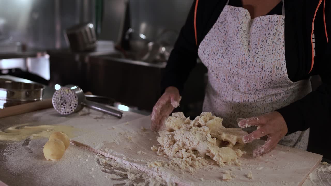 一名妇女在意大利面厂内揉面，准备做新鲜的土豆团