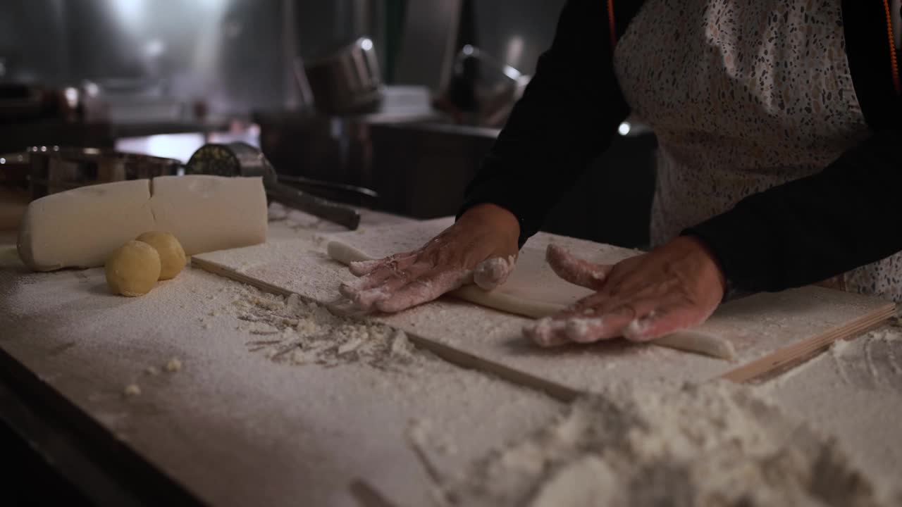 一名妇女在意大利面厂内揉面，准备做新鲜的土豆团