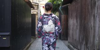 日本妇女在汤田走在狭窄的小路上-后视镜和向后看