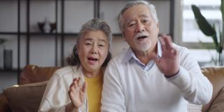 亚洲成熟的老夫妇在家里看着摄像机说话。在线聊天中的视频通话