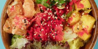 蓝色背景上的Poke碗沙拉。蔬菜切片，红鱼和芝麻。传统的夏威夷美食特写。健康的素食。亚洲素食生餐轮换
