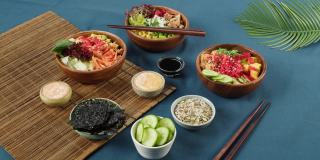煮熟的poke碗与切片蔬菜，鱼和绿叶植物，干海藻。传统的夏威夷美食在餐桌上的特写。健康的素食。亚洲素食生食，筷子