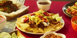 墨西哥食物，传统的墨西哥美食。在配肉和蔬菜的玉米片上放上绿色植物和榨酸橙汁。在餐桌上摆放美式菜肴，快餐