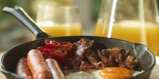 将香料、红辣椒倒在煎蛋上。烹饪传统的全英式早餐特写。英国国菜，培根和香肠。美式酒吧或咖啡馆，快餐