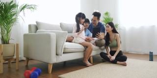 可爱的亚洲孩子和父母一起用数码平板电脑玩游戏。