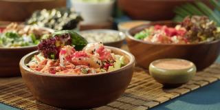 吃戳碗特写，用筷子拿虾，蘸酱。由切成片的蔬菜、鱼和绿叶植物制成的传统夏威夷菜肴。健康的素食。亚洲素食生食