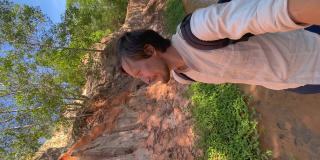 垂直视频。Slowmotion。在越南南部的梅内村，一名男性游客正在参观沙漠边界的红峡谷或仙女溪。用手机拍的。