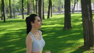 穿着运动上衣的健美女子在公园慢跑视频素材模板下载