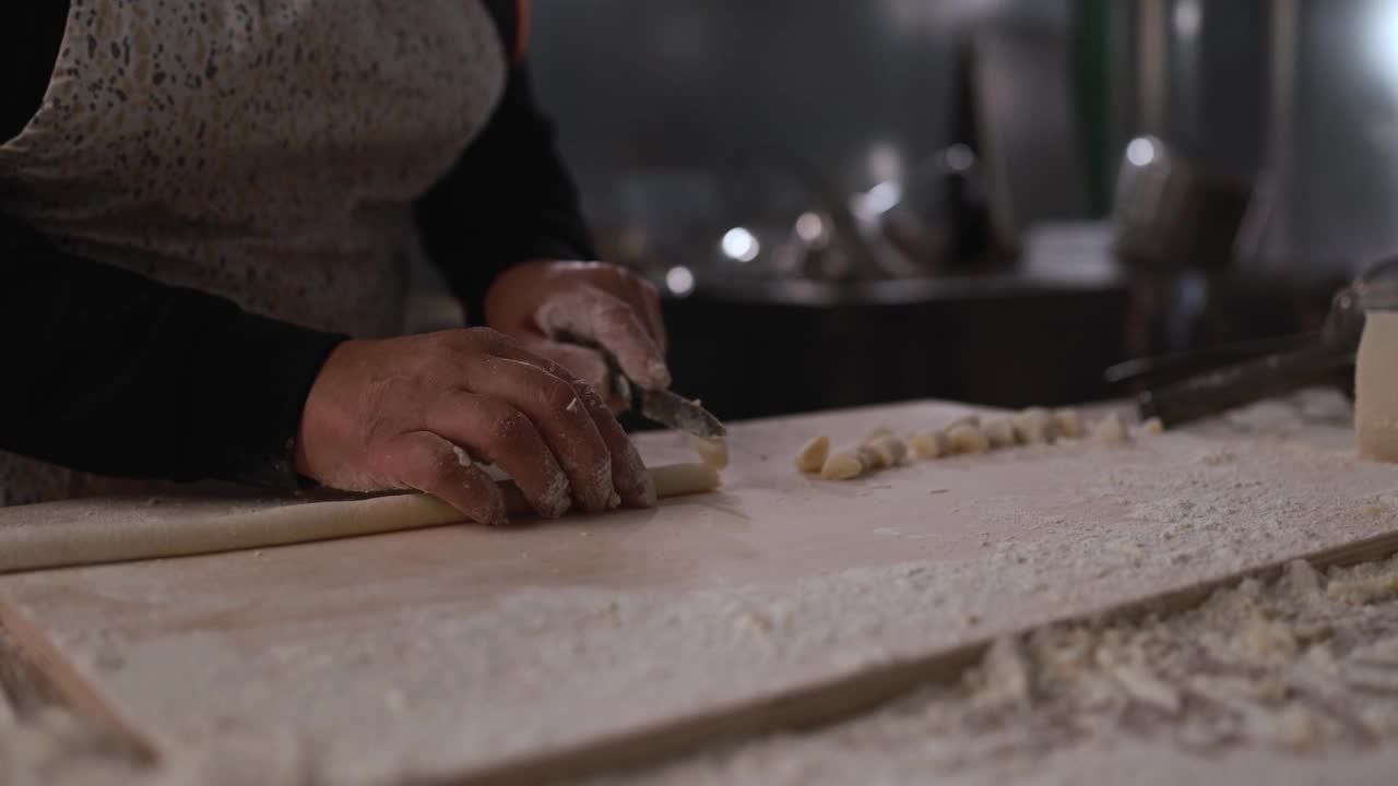 在意大利面厂内，一名妇女正在为新鲜的土豆团准备和切面团