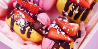 糖果盒，手工制作的精美食品，马卡龙，新鲜草莓和蓝莓装饰巧克力，精致的黄色和粉红色蛋糕，糖和健康食品
