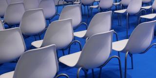 蓝色背景上的白色空椅子排成一排