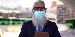 为了应对新冠肺炎疫情，在公交车站，年长的企业人士戴着安全口罩，面带微笑
