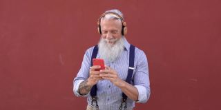 老年潮人使用手机和无线耳机听音乐-老年人享受技术趋势