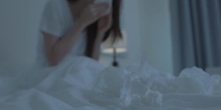 亚洲生病的女孩穿着睡衣醒来在床上打喷嚏。有魅力的年轻女子感觉不舒服，并且患有过敏症，睡觉时用纸巾捂住鼻子。