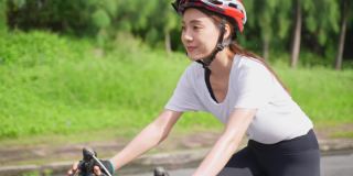 亚洲年轻美丽的女子在公园里为了健康骑自行车。感到愉悦放松和自由。