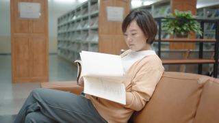 亚洲女人在图书馆的书架上看书视频素材模板下载