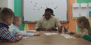非裔美国教师和一群孩子坐在教室的桌子旁学习数字