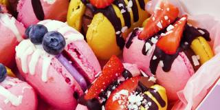 糖果盒，手工制作的精美食品，马卡龙，新鲜草莓和蓝莓装饰巧克力，精致的黄色和粉红色蛋糕，糖和健康食品