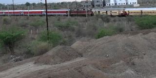 两辆黄色和红色的印度火车在相反的方向经过。