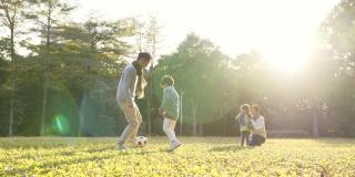 一个亚洲小男孩和爸爸在公园里踢足球