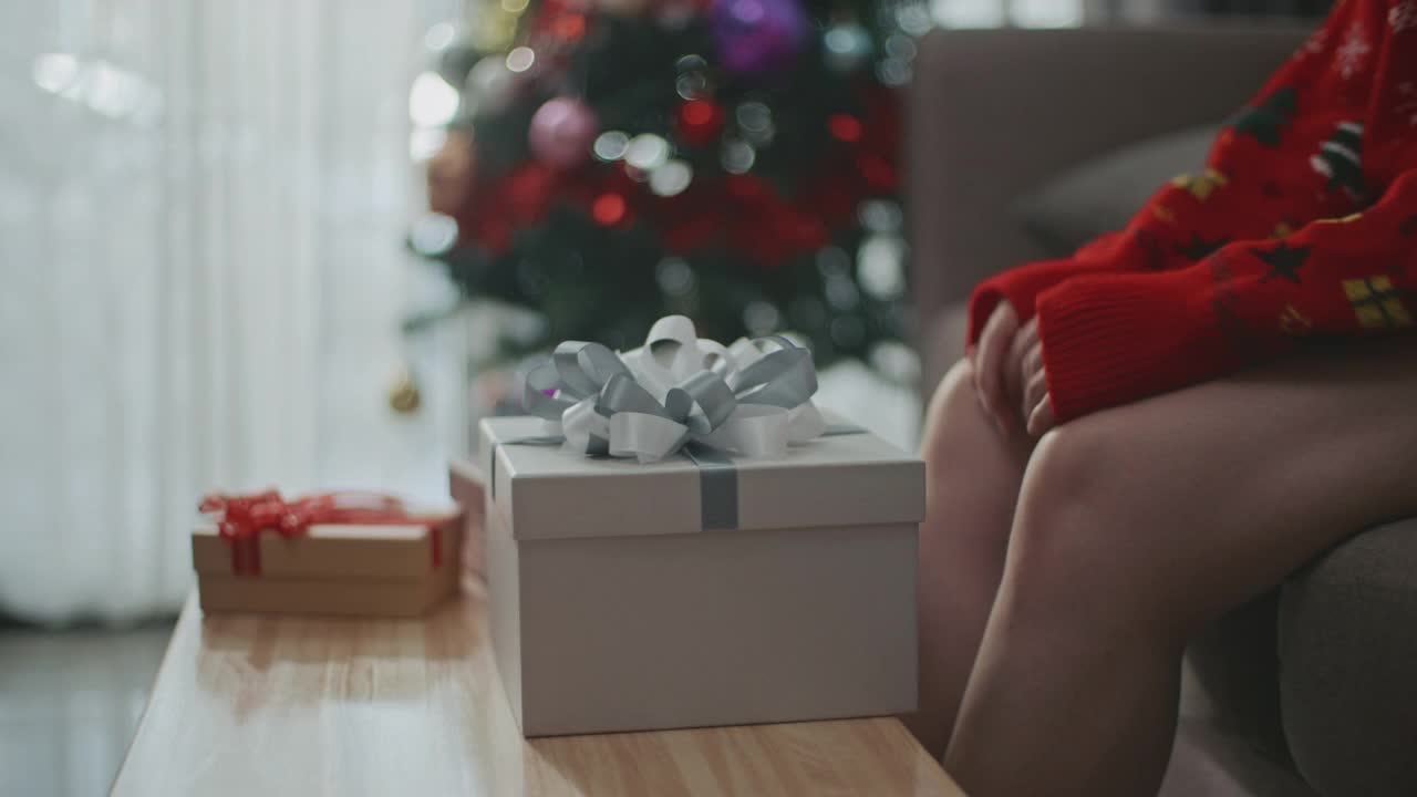 快乐的亚洲女人在圣诞节打开家里的礼品盒