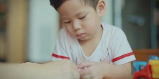 在新冠肺炎疫情期间，为了防止细菌传播，男婴们在客厅里用彩色笔画画。照顾孩子。