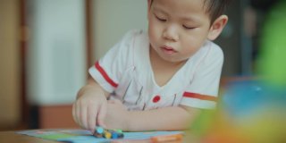 在新冠肺炎疫情期间，为了防止细菌传播，男婴们在客厅里用彩色笔画画。照顾孩子。