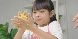快乐的亚洲孩子在家里一起学习做饼干，女孩在她的手中打面团。