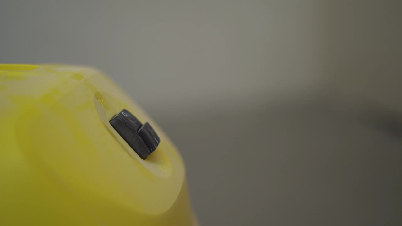 一只戴着建筑手套的无名建筑工人的手打开了一台黄色的工业吸尘器。建筑装修，房地产概念
