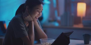 中国年轻的成年女性晚上坐在公寓里用笔记本电脑看网络电影