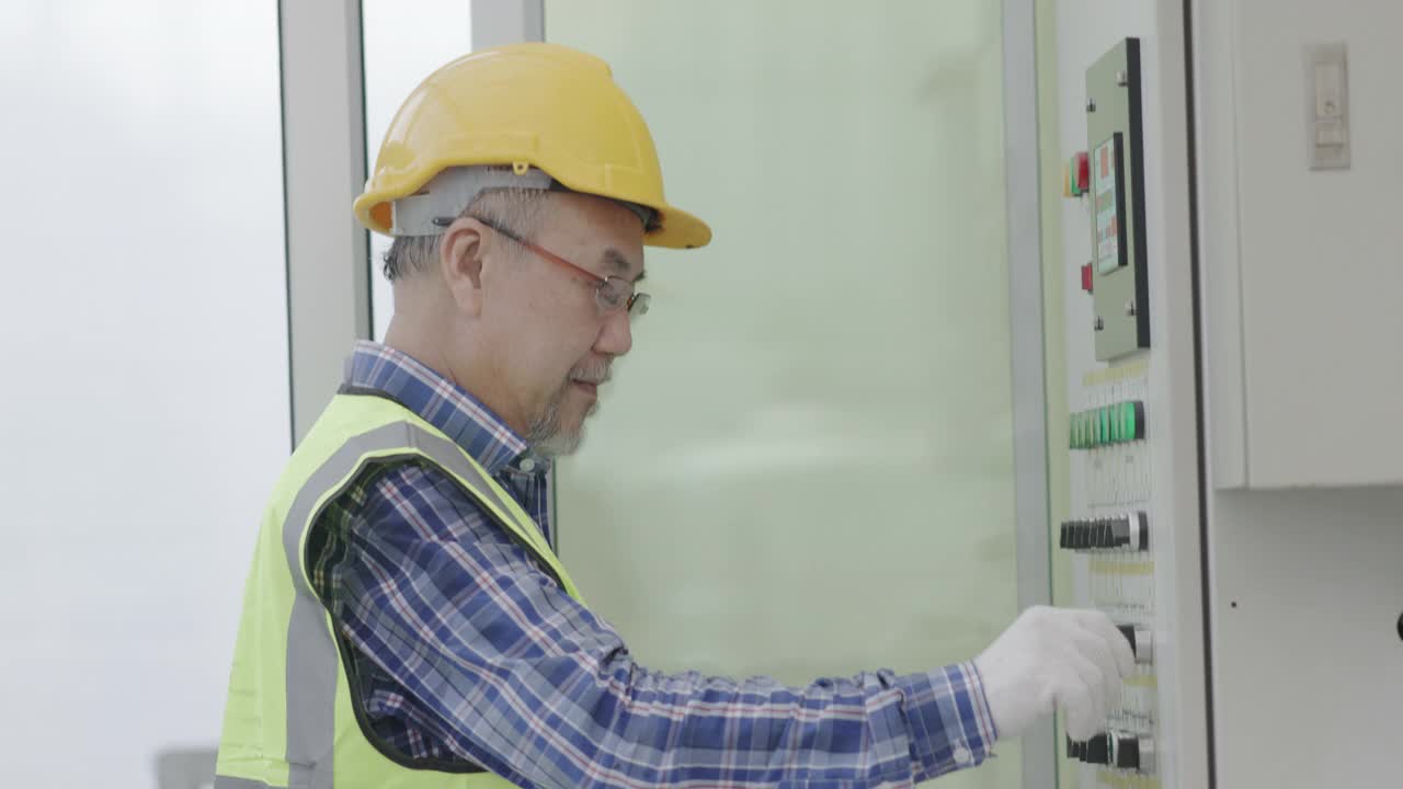 资深亚洲工程师正在专业使用平板电脑检查工业机械的按键。技术员检查机房准备情况。概念蓝领