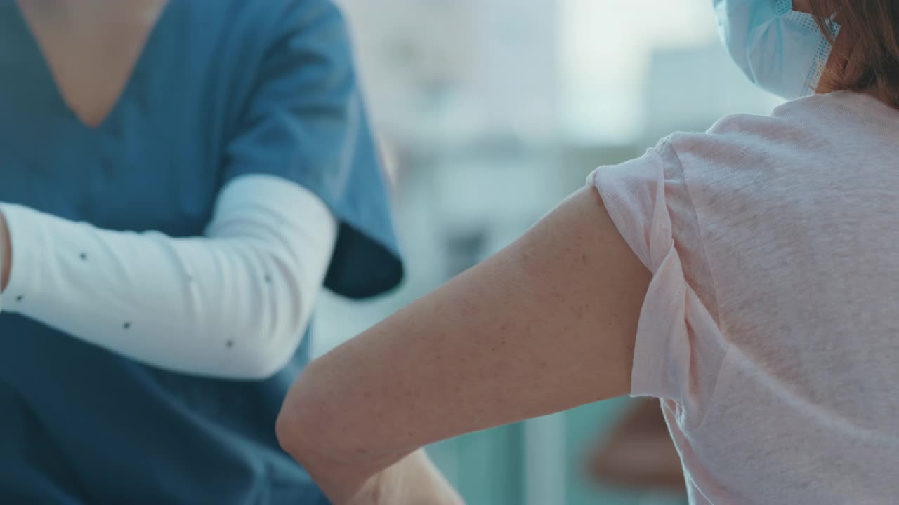 一段4k视频显示，一名不认识的护士在诊所给她的病人注射新冠疫苗