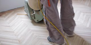 修理工用砂光机修复拼花地板。