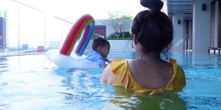 亚洲男婴和妈妈一起在游泳池里学游泳