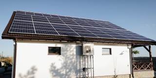 全新的现代住宅，屋顶有蓝色闪亮的太阳能光伏板系统。可再生生态绿色能源生产理念。